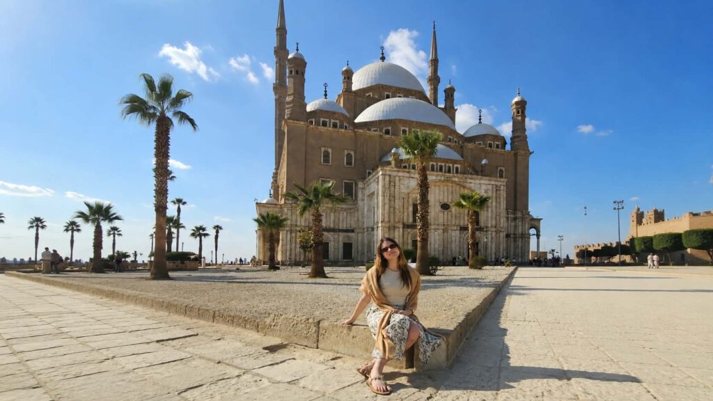 Turistas vestidos adequadamente, com ombros e pernas cobertos, visitando o interior de uma mesquita no Egito