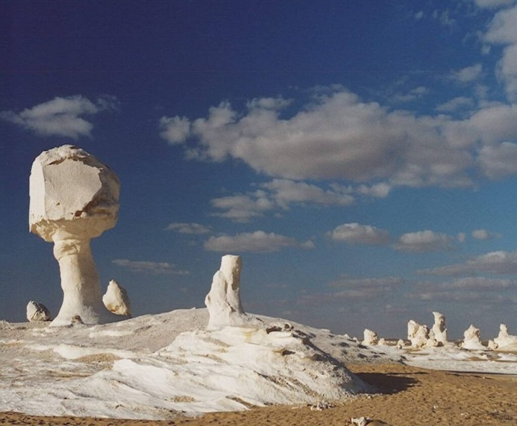 Safari no Deserto Preto e Branco do Egito em veículo 4x4, com paisagens únicas de montanhas vulcânicas, formações calcárias e acampamento beduíno sob o céu estrelado.